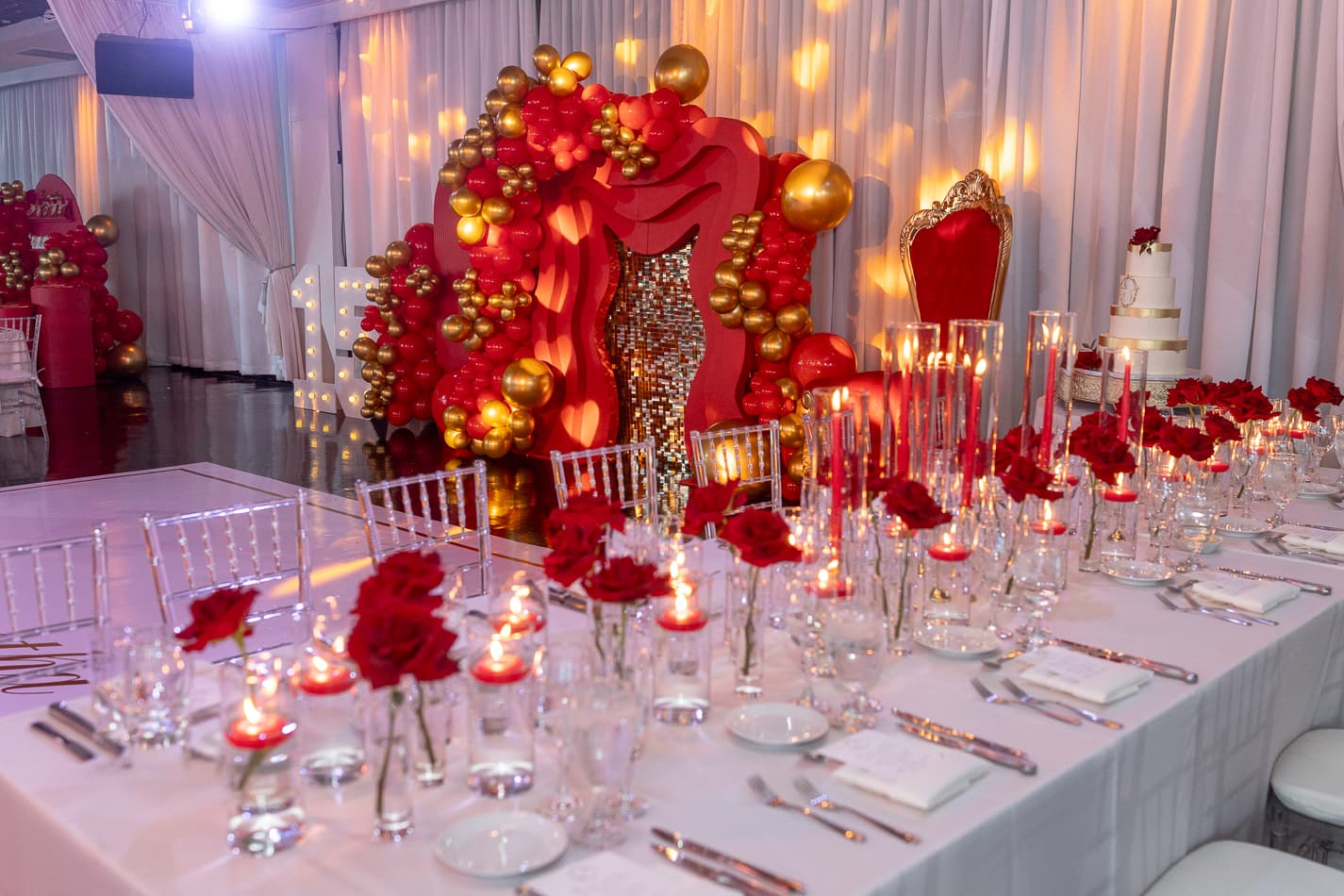 Quinceañera head table in red and gold with a balloon arch