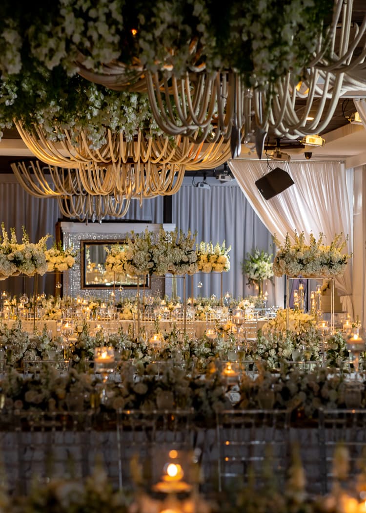 Long reception tables layered with white florals and candlelight